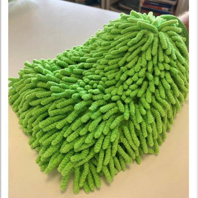 Green microfiber cleaning pad on a surface with a blurred background