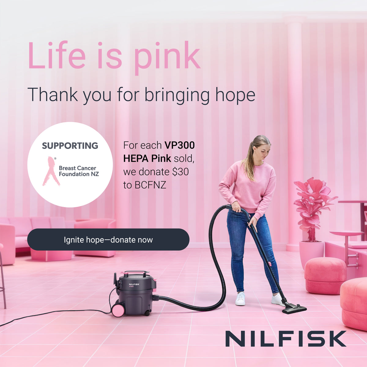 A woman in a pink sweatshirt and blue jeans uses a Nilfisk HEPA Pink vacuum cleaner in a pink room. The image includes promotional text for Breast Cancer Foundation NZ and the Nilfisk brand.