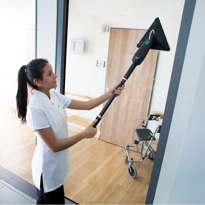 Person cleaning a glass door with a squeegee in a modern interior setting.
