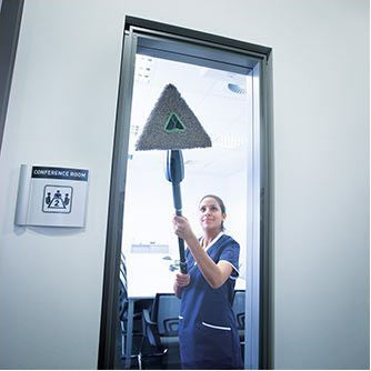 Person cleaning a glass door with a squeegee in a professional setting.