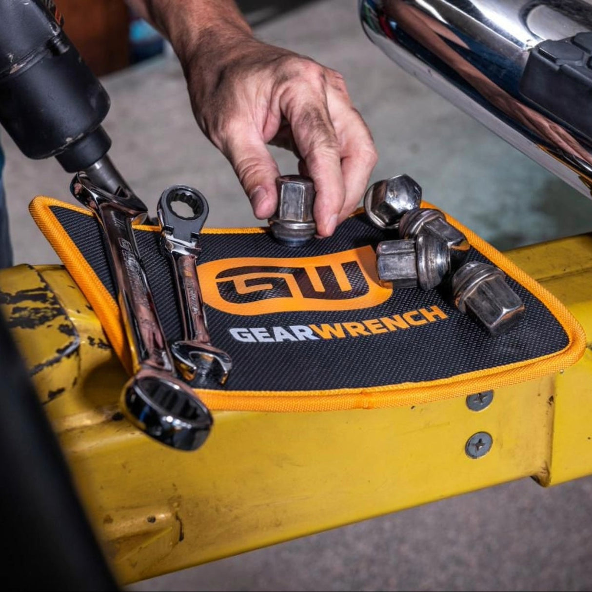 Person using a GearWrench tool set on a yellow stand with a drill in hand.