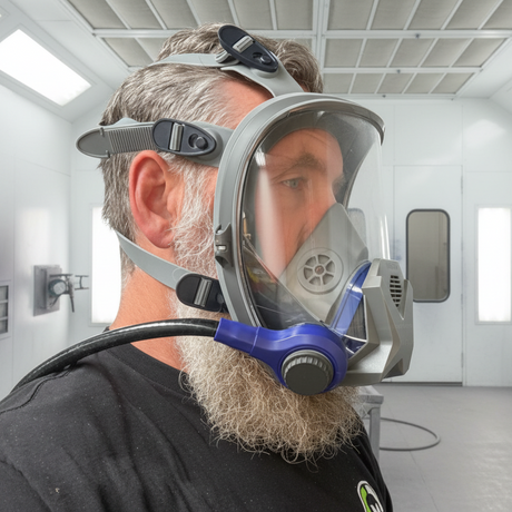 Person wearing a full-face respiratory mask in a spray booth.