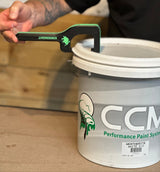 Person using a paint pail opener on a CCM Performance Paint Systems bucket.