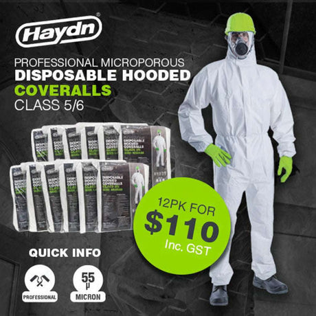 A person wearing a white hooded disposable coverall suit with green gloves and a hat, standing next to a stack of product packages.