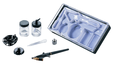 An airbrush kit with a black and gold airbrush pen, two small glass bottles with black caps, a black hose, a small plastic pipette, a metal cap, and a clear plastic storage tray on a white background.