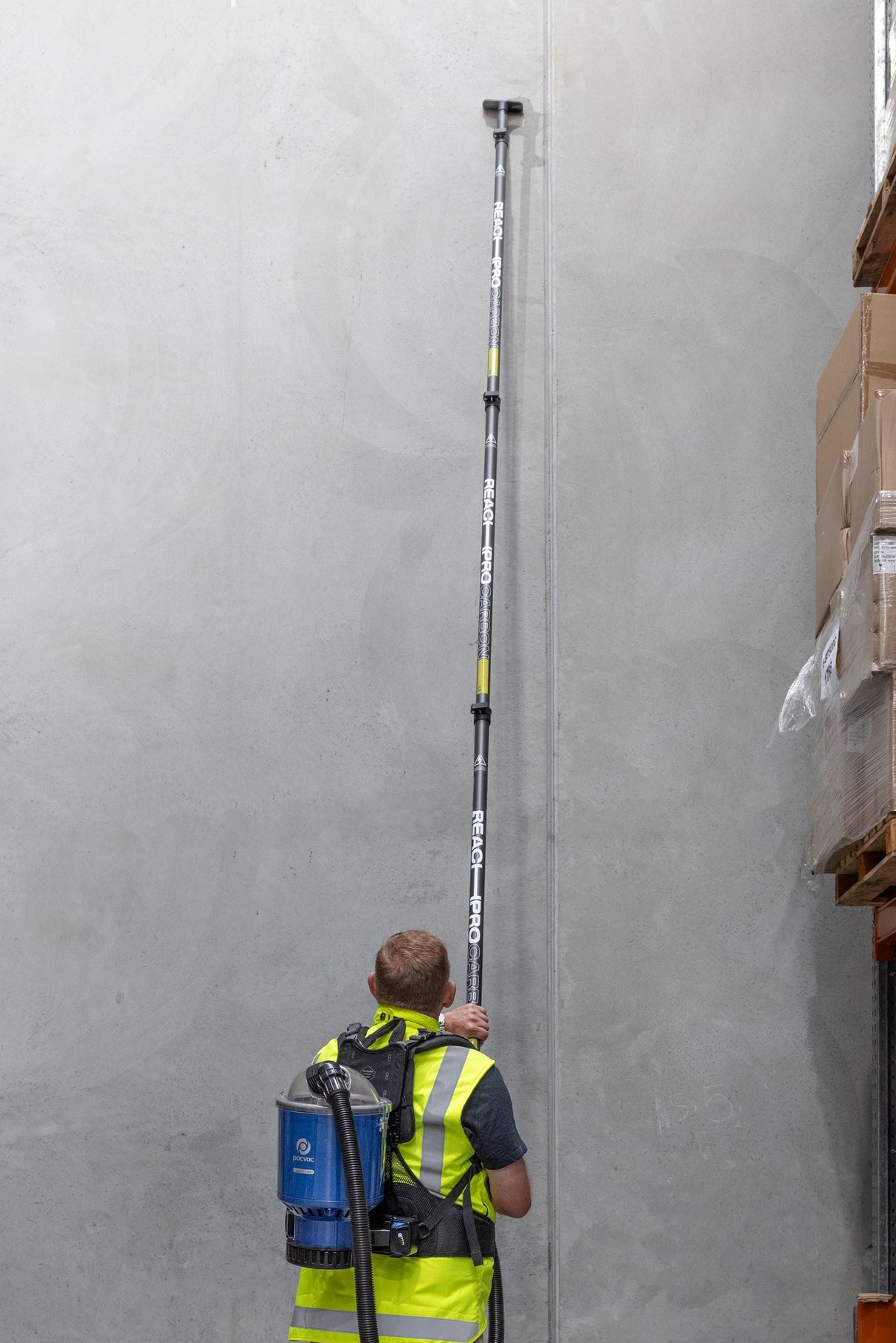 Person in a warehouse using a long measuring device against a wall.