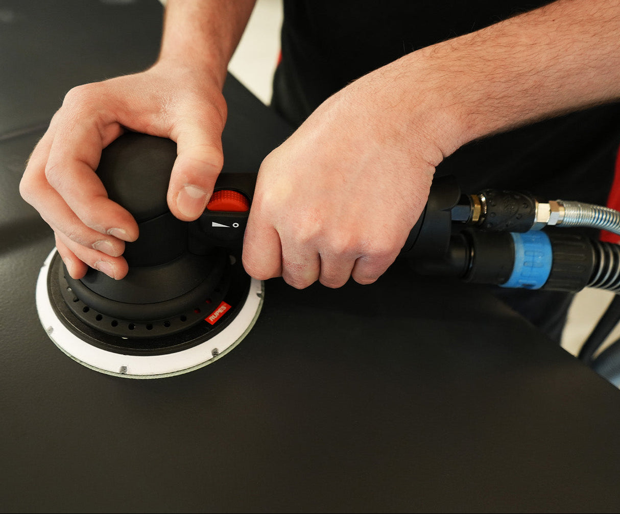 Person using a sander on a car surface