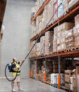 Person using a long-handled tool to interact with items on high shelves in a warehouse.