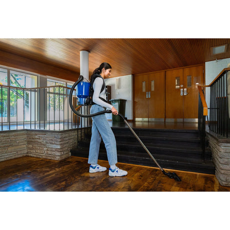 Person using a vacuum cleaner on a wooden floor in a home setting
