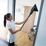 Person cleaning a glass door with a squeegee in a modern interior setting.