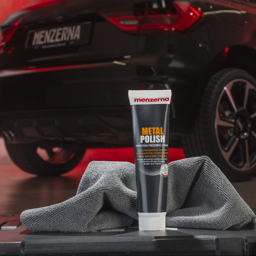 Menzerna metal polish tube with a car in the background