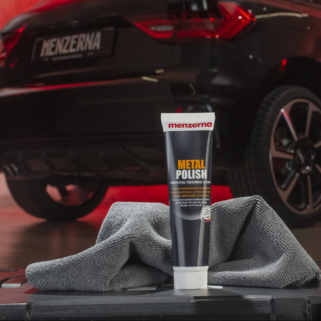 Menzerna metal polish tube with a car in the background